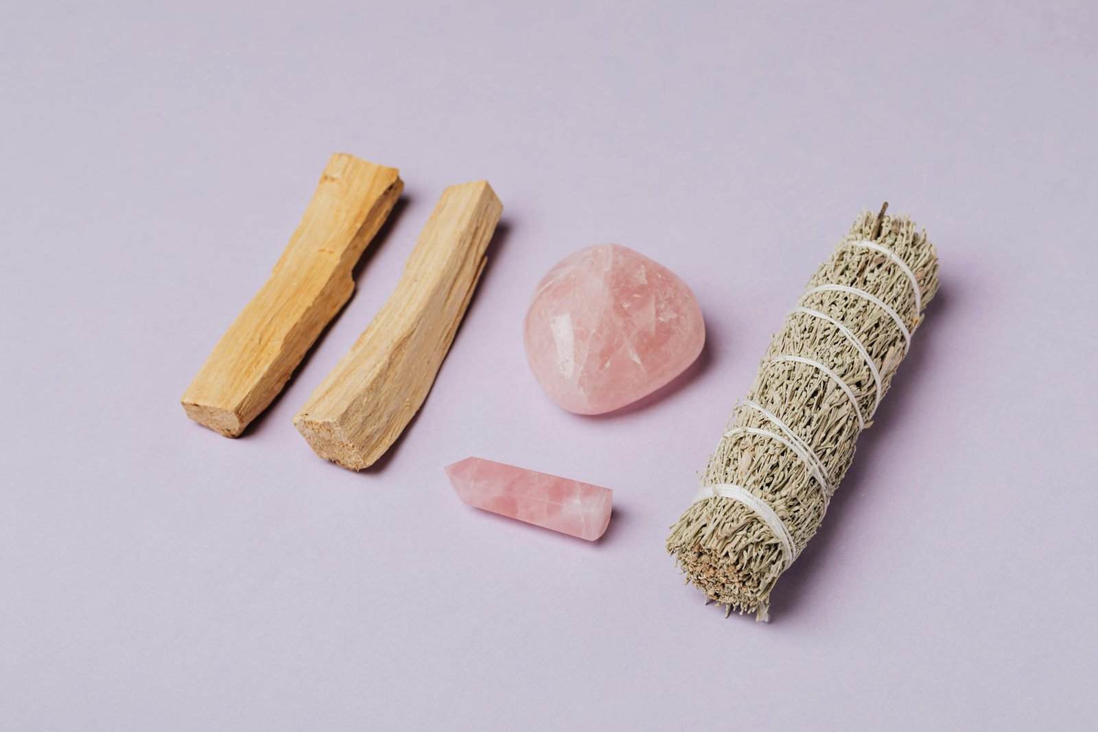 Rose quartz and sage arrangement on lavender backdrop, ideal for meditation and rituals.